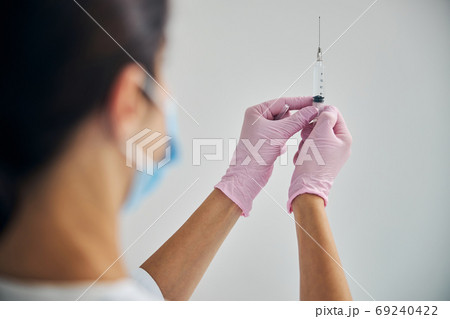 Dermatologist in a face mask preparing for giving an injection Dermatologist in a face mask preparing for giving an injection 69240422