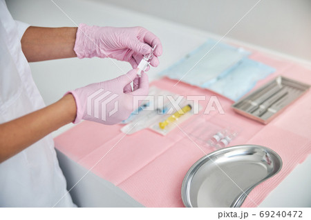 Professional cosmetologist preparing for administering an injection 69240472