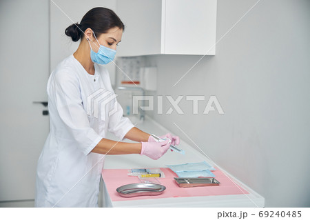 Female dermatologist unpacking a sealed biopsy tool Female dermatologist unpacking a sealed biopsy tool 69240485