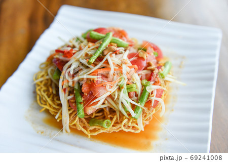Papaya salad spicy on crispy noodles on white plate , Thai food 69241008