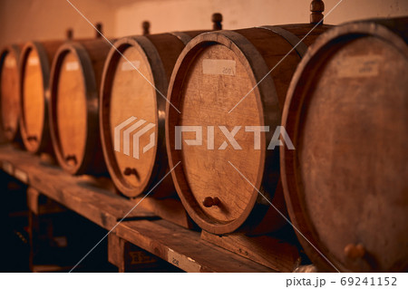 Wooden wine barrels on shelf in wine cellar 69241152