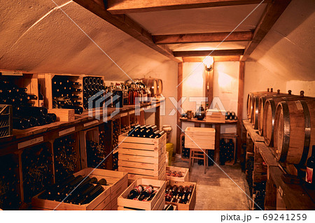 Storage room with wine in bottles and barrels. 69241259