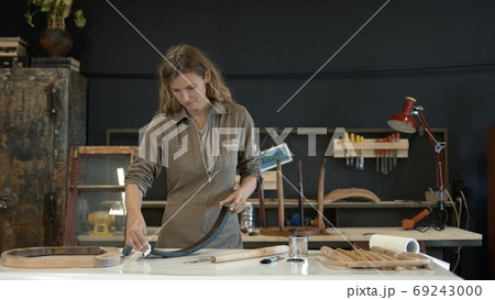 Woman painting a wooden chair leg in a workshop, restoration process Woman painting a wooden chair leg in a workshop, restoration process 69243000