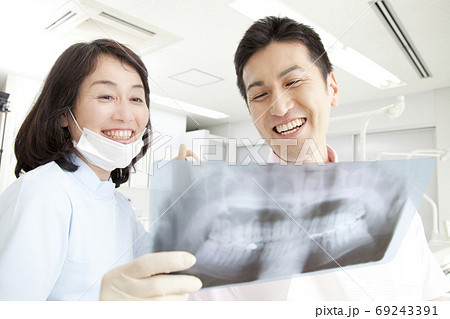 患者にレントゲンで説明する歯科医 69243391