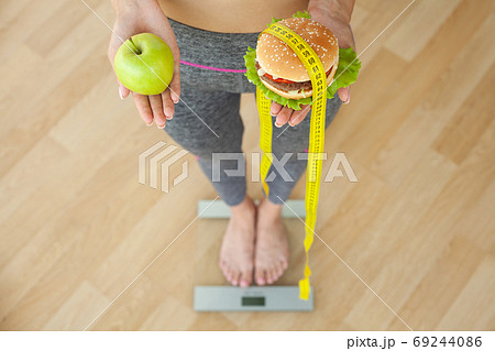 Diet concept, woman holding a choice of harmful hamburger and fresh apple Diet concept, woman holding a choice of harmful hamburger and fresh apple 69244086