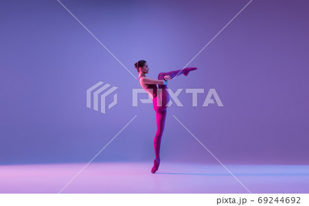 Young and graceful ballet dancer isolated on purple studio background in neon light 69244692