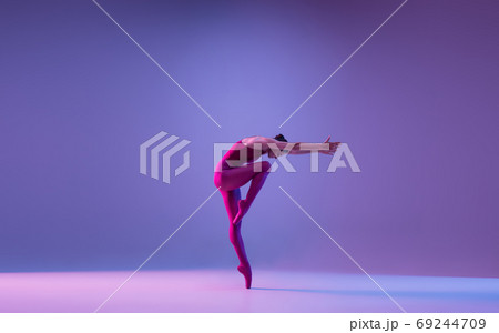 Young and graceful ballet dancer isolated on purple studio background in neon light Young and graceful ballet dancer isolated on purple studio background in neon light 69244709