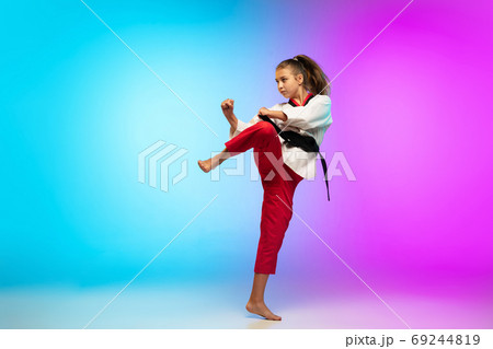 Karate, taekwondo girl with black belt isolated on gradient background in neon light Karate, taekwondo girl with black belt isolated on gradient background in neon light 69244819
