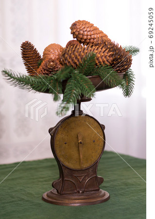 Stylish antique decor with pine cones. A handful of pine cones on an antique bronze scale Stylish antique decor with pine cones. A handful of pine cones on an antique bronze scale 69245059