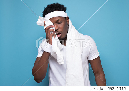 African young sportman wipes sweat off his face with a towel after exercise 69245556