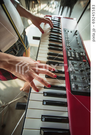 Woman recording music, singing and playing piano while standing in loft workplace or at home 69245583