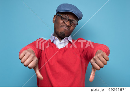 African man giving thumbs down gesture, looking with negative facial expression African man giving thumbs down gesture, looking with negative facial expression 69245674