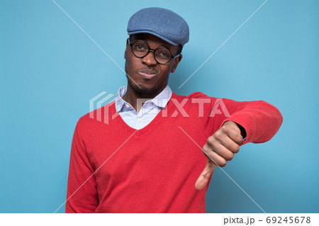 African man giving thumbs down gesture, looking with negative facial expression African man giving thumbs down gesture, looking with negative facial expression 69245678