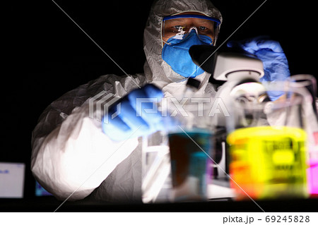 A man in a laboratory looks through a microscope 69245828