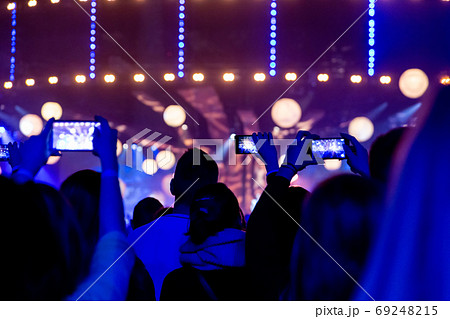 Silhouettes of crowds of spectators at a concert with smartphones in their hands. 69248215