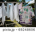 Baby clothes and diapers are exposed to the sun in the backyard. 69248606