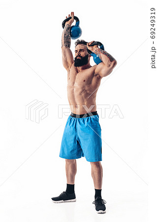 Muscular shirtless tattooed bearded male athlete bodybuilder workout with kettlebell on a white background. Muscular shirtless tattooed bearded male athlete bodybuilder workout with kettlebell on a white background. 69249319