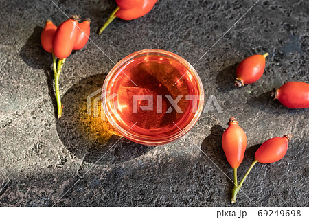 A bowl of rosehip seed oil with fresh rosehips 69249698