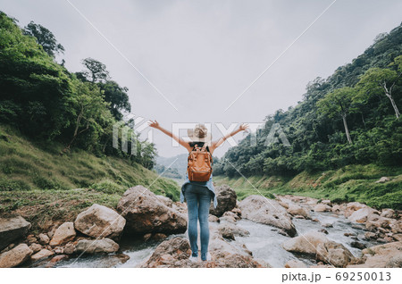 woman with arm raised feeling free enjoying nature 69250013