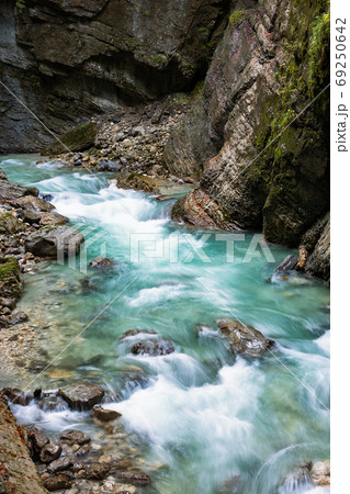 Clean, beautiful, mountain river flows through a rocky gorge Partnachklamm in Germany incised by a mountain stream near the Garmisch-Partenkirchen. Clean, beautiful, mountain river flows through a rocky gorge Partnachklamm in Germany incised by a mountain stream near the Garmisch-Partenkirchen. 69250642