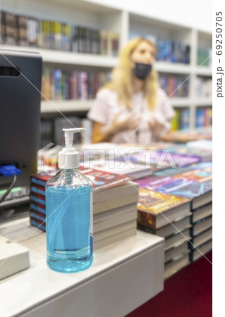 Large bottle of sanitizer with hand gel on background modern urban bookshop. Hygiene, personal protection concept, prevention of transmission of infectious diseases Large bottle of sanitizer with hand gel on background modern urban bookshop. Hygiene, personal protection concept, prevention of transmission of infectious diseases 69250705