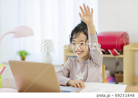 自宅でパソコンを見ながら勉強する女の子の写真素材