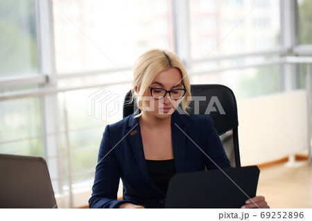 smiling blonde businesswoman with glasses using laptop in the office smiling blonde businesswoman with glasses using laptop in the office 69252896