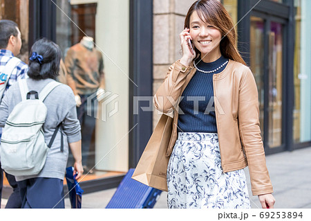 路上で電話をしながらショッピングを楽しむ女性 路上で電話をしながらショッピングを楽しむ女性 69253894