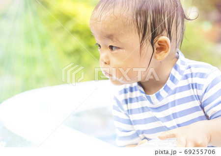 外で水遊びでずぶ濡れの子供　何かに気を取られて真剣なまなざしの子供のアップ 69255706