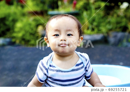 外で遊んで自慢げな表情をしている子供 水遊びしてずぶ濡れの子供の写真素材