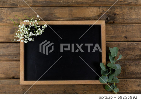 View of a black board surrounded by flowers on wood table background View of a black board surrounded by flowers on wood table background 69255992