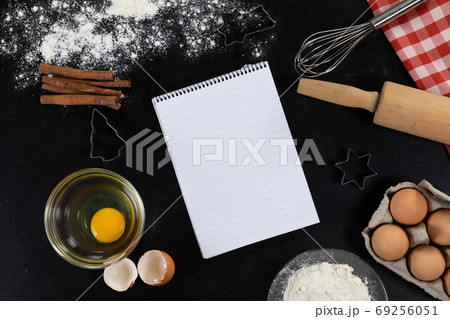 View of an empty notebook page with ingredients prepared for baking cookies, arranged on a plain bla View of an empty notebook page with ingredients prepared for baking cookies, arranged on a plain bla 69256051