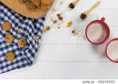 View of cookies, spoons with dried fruits and nuts and two mugs with milk on wooden View of cookies, spoons with dried fruits and nuts and two mugs with milk on wooden 69256093