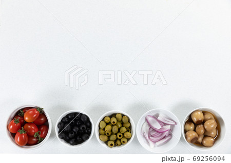 View of a six bowls with fresh tomatoes, olives, nuts and seasoning on plain white surface View of a six bowls with fresh tomatoes, olives, nuts and seasoning on plain white surface 69256094