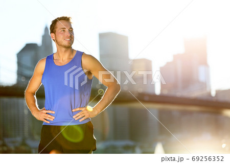 Sport athlete man running looking away at New York City - Brooklyn Bridge and Manhattan skyline copy space. Active healthy lifestyle fit fitness runner outside training fitness workout outdoor in NYC. 69256352