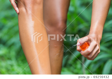 Woman spraying mosquito repellent on leg skin. Woman using Insect repellent bug spray bottle on legs, body and clothing outdoor in nature forest. Prevention for zika virus affecting tropical areas. Woman spraying mosquito repellent on leg skin. Woman using Insect repellent bug spray bottle on legs, body and clothing outdoor in nature forest. Prevention for zika virus affecting tropical areas. 69256432