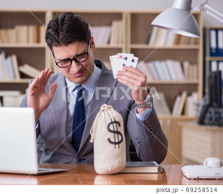 The businessman gambling playing cards at work 69258514