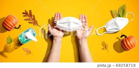 Person holding a mask with autumn pumpkins and leaves Person holding a mask with autumn pumpkins and leaves 69258719