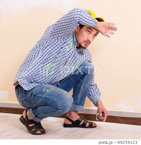 Young contractor sanding wall down with sandpaper Young contractor sanding wall down with sandpaper 69259123