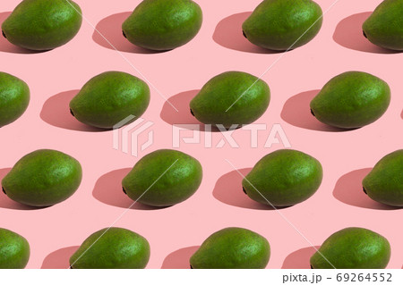 Trending style pattern of a whole green avocado on a pink background with hard light. Creative food texture. Trending style pattern of a whole green avocado on a pink background with hard light. Creative food texture. 69264552