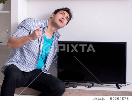 Man trying to fix broken tv 69264878