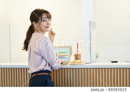 アクリルパーテーションのあるカフェで仕事をする女性 69265015