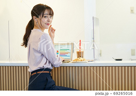 アクリルパーテーションのあるカフェで仕事をする女性 69265016