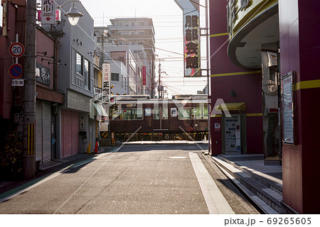 遮断機の降りる踏切を通過する阪急電車と駅周辺の風景・阪急服部天神駅駅前 69265605