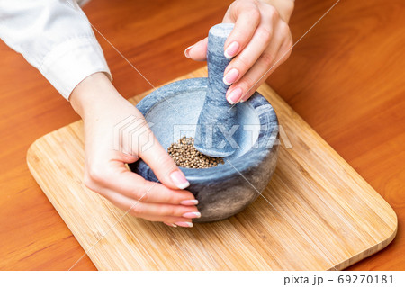 Hands of woman grinding pepper in mortar 69270181