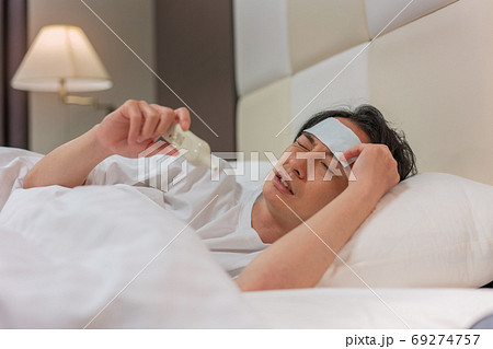 夜、体温計で熱を測る若い男性 夜、体温計で熱を測る若い男性 69274757