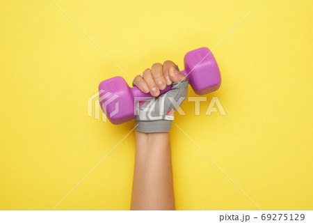 female hand in a pink sports glove holds a purple one kilogram d 69275129