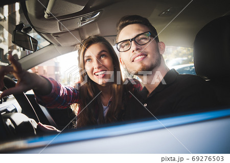 Young caucasian couple in car having fun on road Young caucasian couple in car having fun on road 69276503