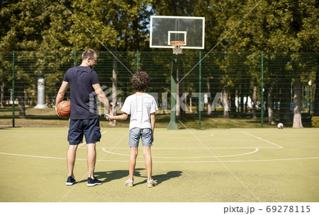 Man posing with son on basketball pitch back view Man posing with son on basketball pitch back view 69278115
