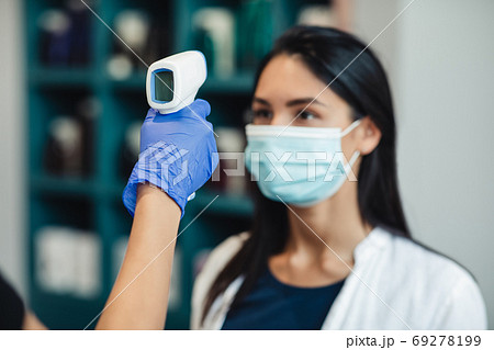 Worker holding ultrared heat scanner opposite woman client head 69278199